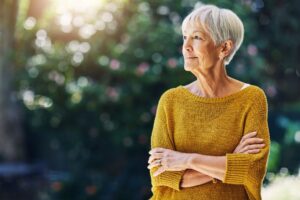 Older woman looking to the side with a tree in the background

